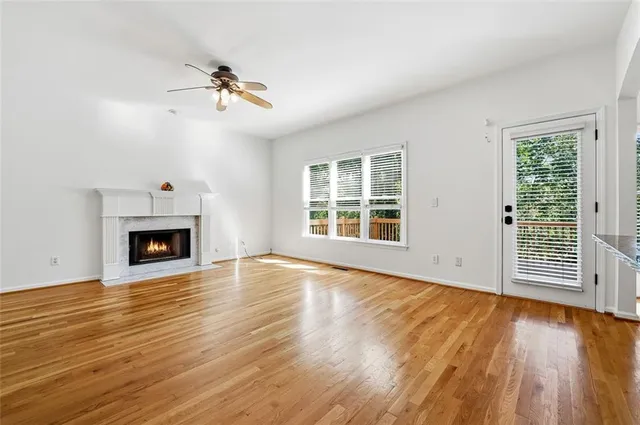 a view of an empty room with wooden floor fireplace and a window