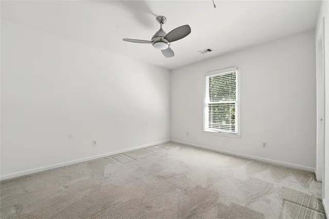an empty room with ceiling fan and window