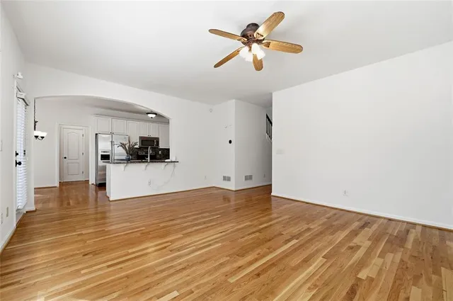 a view of empty room with wooden floor and ceiling fan