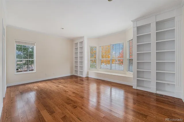 a view of an empty room with a window and wooden floor