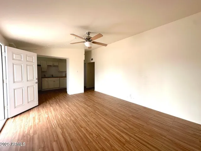a view of an empty room with a window and wooden floor