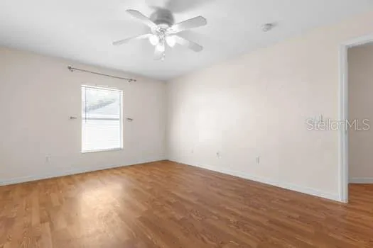 a view of empty room with wooden floor and window