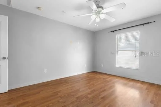 a view of an empty room with window and wooden floor