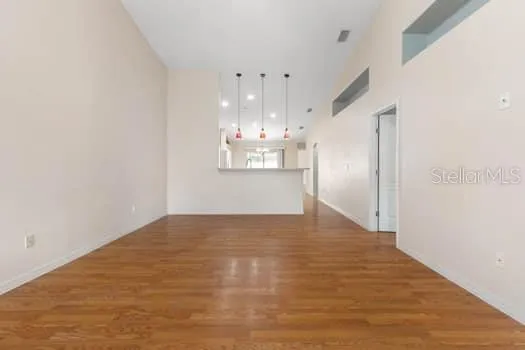 a view of an empty room with a window and wooden floor