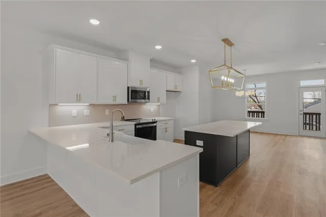 a large white kitchen with kitchen island a sink stainless steel appliances and cabinets