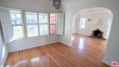 a view of an empty room with a window and wooden floor