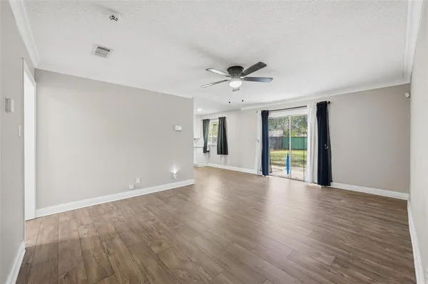 a view of an empty room with window and wooden floor