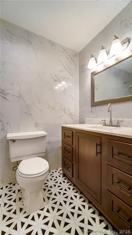 a bathroom with a granite countertop sink a mirror and a toilet