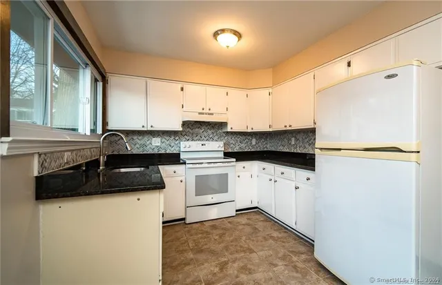 a kitchen with granite countertop white cabinets and white appliances