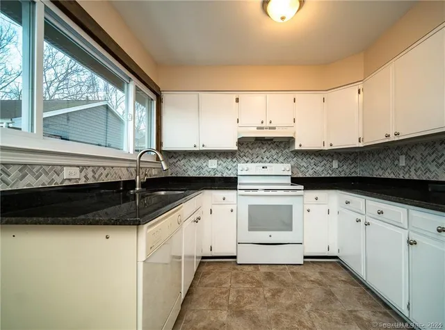 a kitchen with granite countertop a sink a stove and cabinets