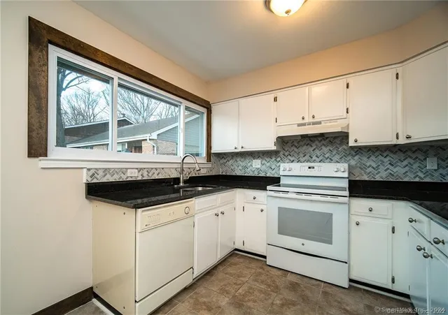 a kitchen with granite countertop white cabinets and white appliances