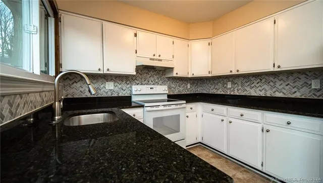 a kitchen with granite countertop white cabinets and black appliances