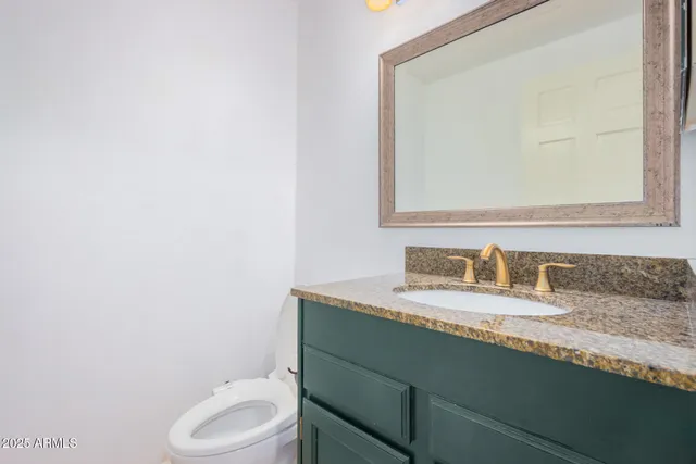 a bathroom with a granite countertop toilet sink and mirror
