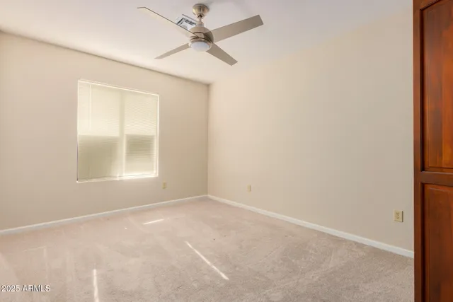 an empty room with a window and a fan