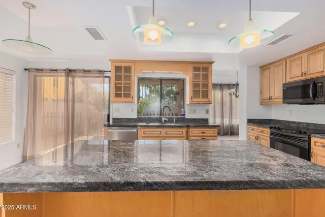 a view of a kitchen with kitchen island a large window and stainless steel appliances
