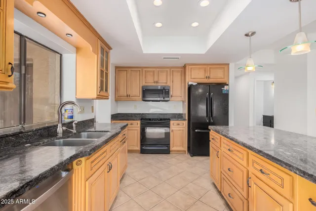 a large kitchen with granite countertop a large counter top stainless steel appliances and cabinets