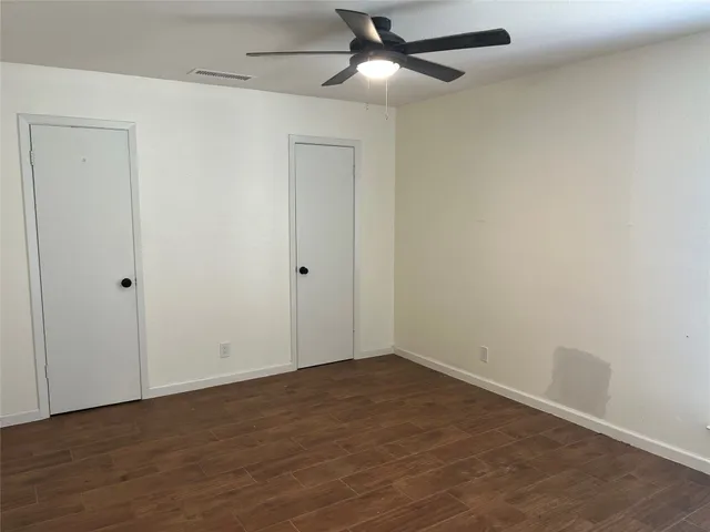 an empty room with wooden floor ceiling fan and window