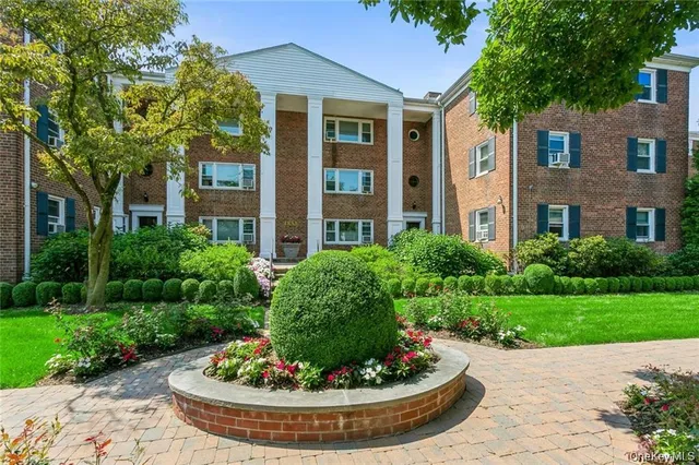 a view of a brick house with a yard and plants