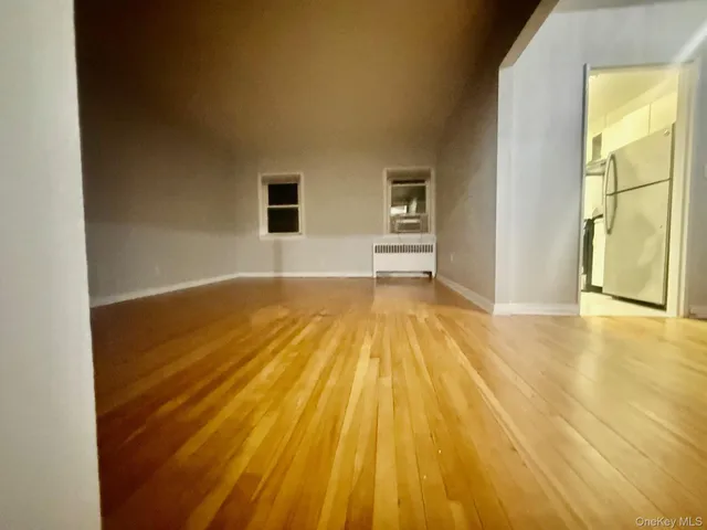 a view of a bedroom with wooden floor and two windows