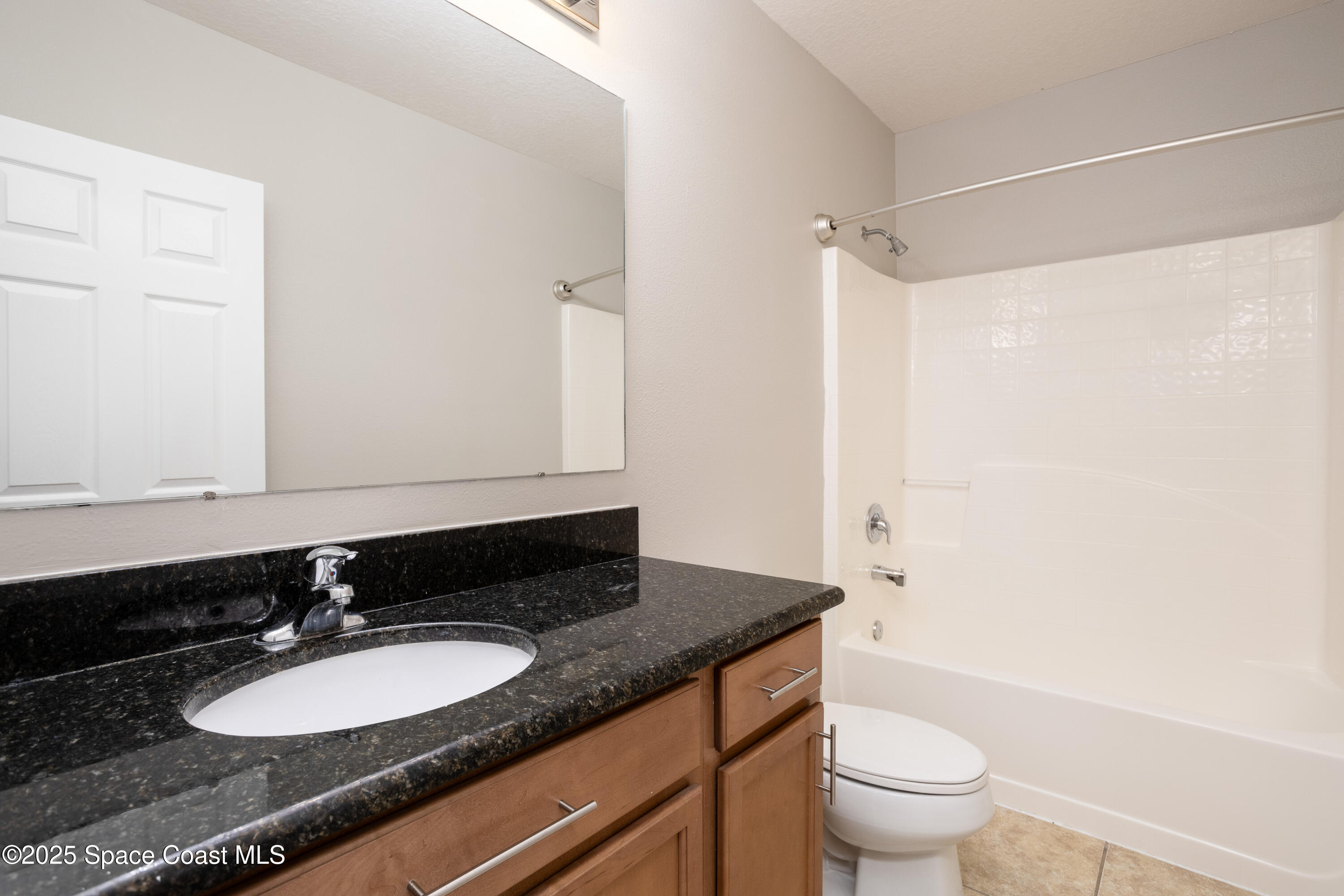 2780 Reston Street, Unit 104 Melbourne, FL 32935 - Photo 20 of 29 a bathroom with a granite countertop sink toilet a mirror and shower