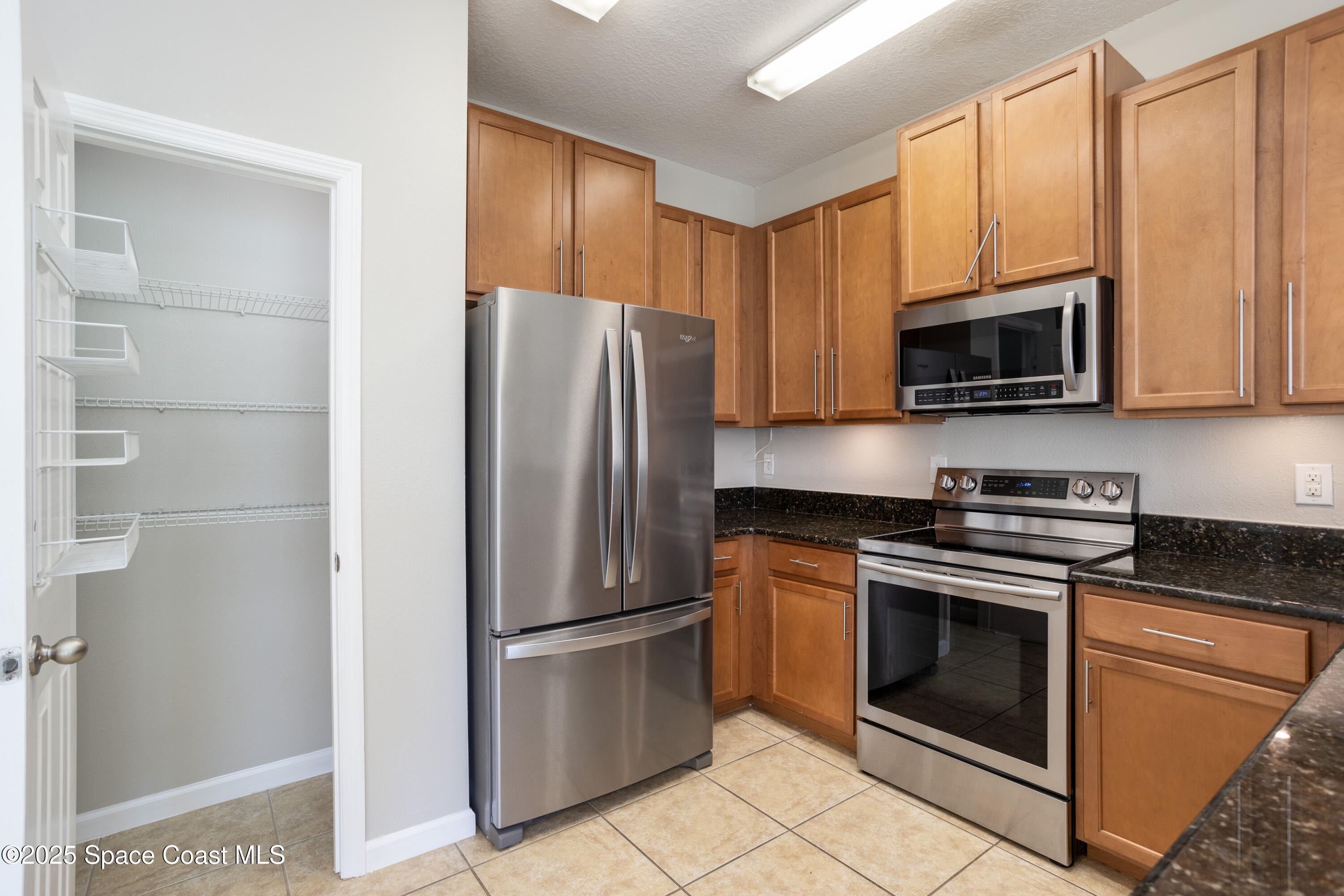 2780 Reston Street, Unit 104 Melbourne, FL 32935 - Photo 6 of 29 a kitchen with stainless steel appliances granite countertop a refrigerator stove and microwave