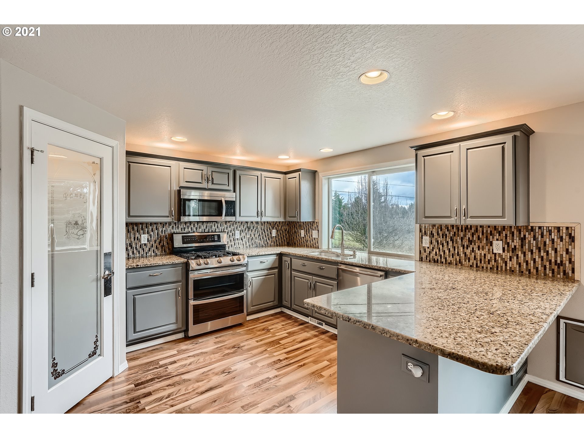2417 North 9th Circle Ridgefield, WA 98642 - Photo 9 of 32 a kitchen with stainless steel appliances granite countertop a stove top oven a sink dishwasher a refrigerator and a dining table with wooden floor