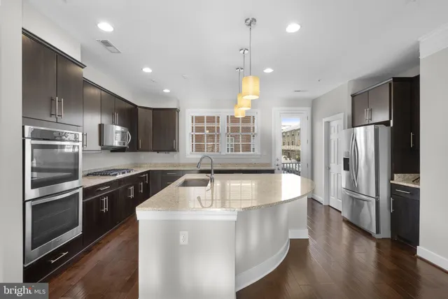 a large kitchen with kitchen island a large counter top space a sink stainless steel appliances and cabinets