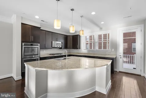 a kitchen with stainless steel appliances granite countertop a sink a stove and a refrigerator