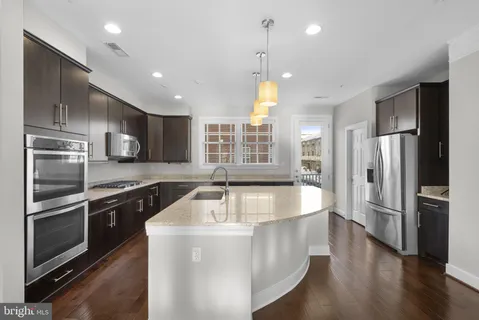 a kitchen with stainless steel appliances granite countertop a sink a oven and a refrigerator