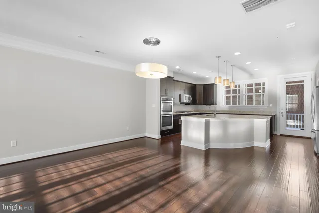 a open kitchen with stainless steel appliances granite countertop a refrigerator a sink dishwasher a stove and white countertops with wooden floor