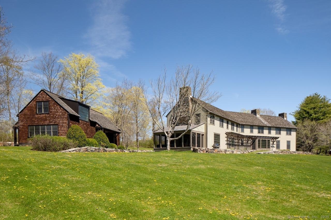 a view of a house with a big yard and large trees