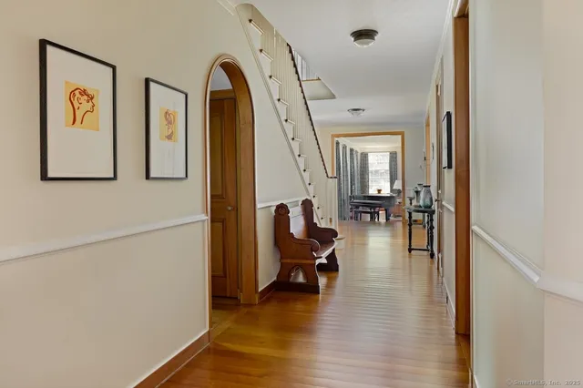 a view of a hallway with couches and dinning table with wooden floor