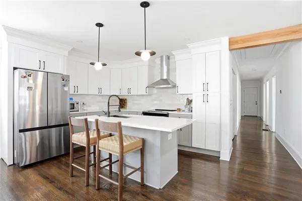 a kitchen with stainless steel appliances granite countertop a refrigerator a sink dishwasher a stove and white cabinets with wooden floor