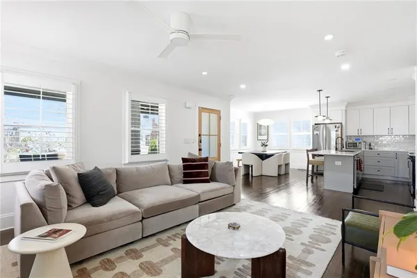 a living room with couches a coffee table and kitchen view with wooden floor