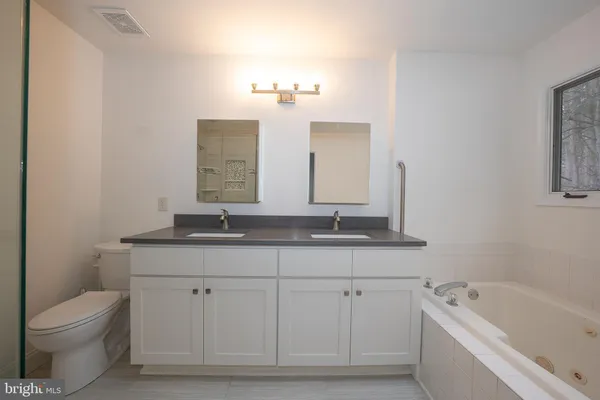 a bathroom with a bathtub a sink a window and mirror