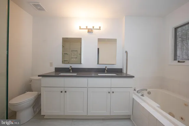 a bathroom with a bathtub a sink a window and mirror