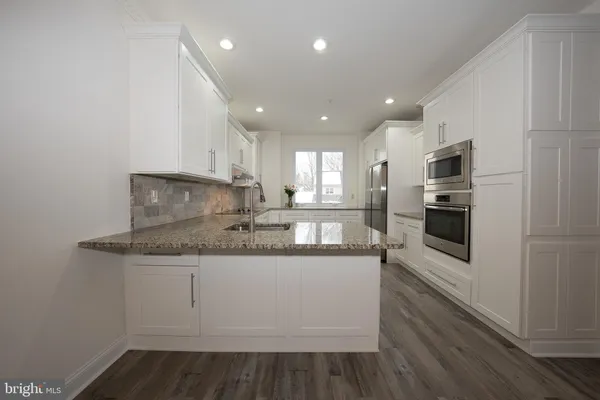 a kitchen with stainless steel appliances granite countertop a sink and a stove top oven with wooden floor