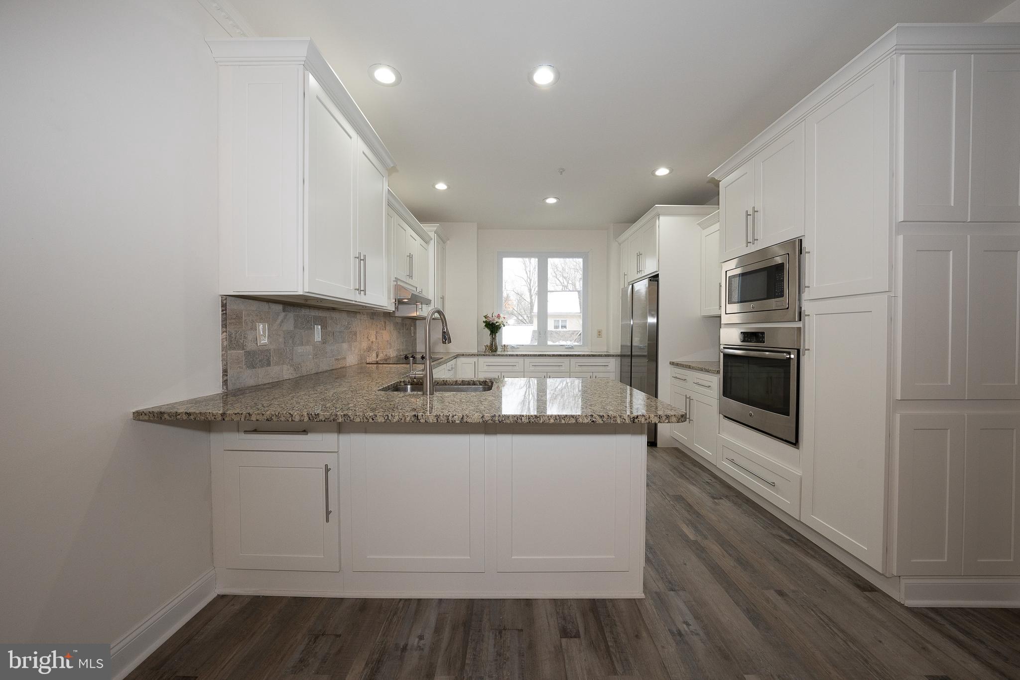 514 Waters Edge Newtown Square, PA 19073 - Photo 4 of 29 a kitchen with stainless steel appliances granite countertop a sink and a stove top oven with wooden floor