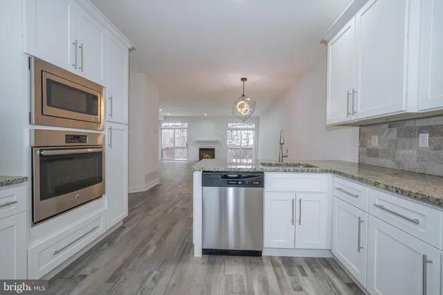 a kitchen with granite countertop white cabinets and stainless steel appliances