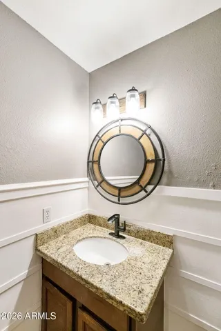 a bathroom with a granite countertop toilet a sink and a mirror