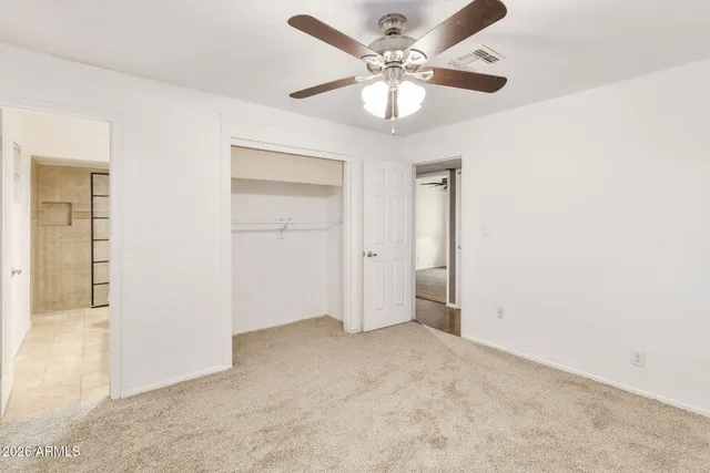 an empty room with windows and fan