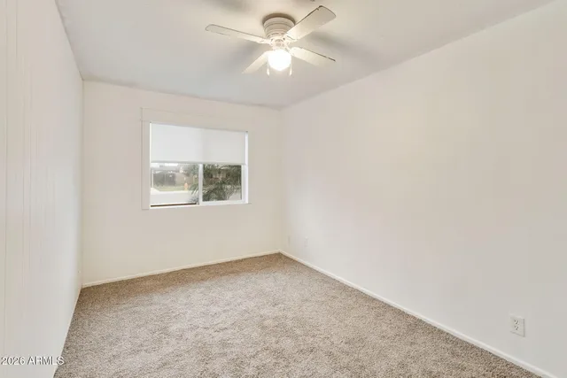 an empty room with a window and a fan