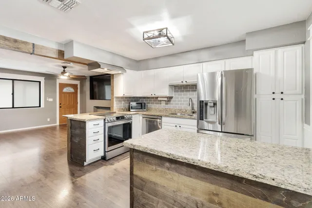 a kitchen with stainless steel appliances granite countertop a refrigerator a stove and a sink