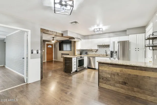 a kitchen with granite countertop a refrigerator and a stove top oven