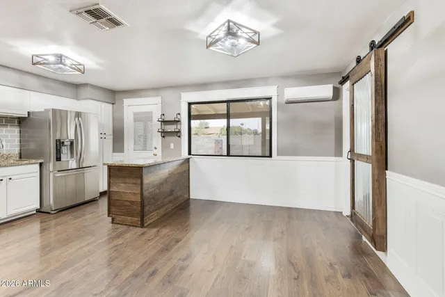 a large white kitchen with wooden floor and stainless steel appliances