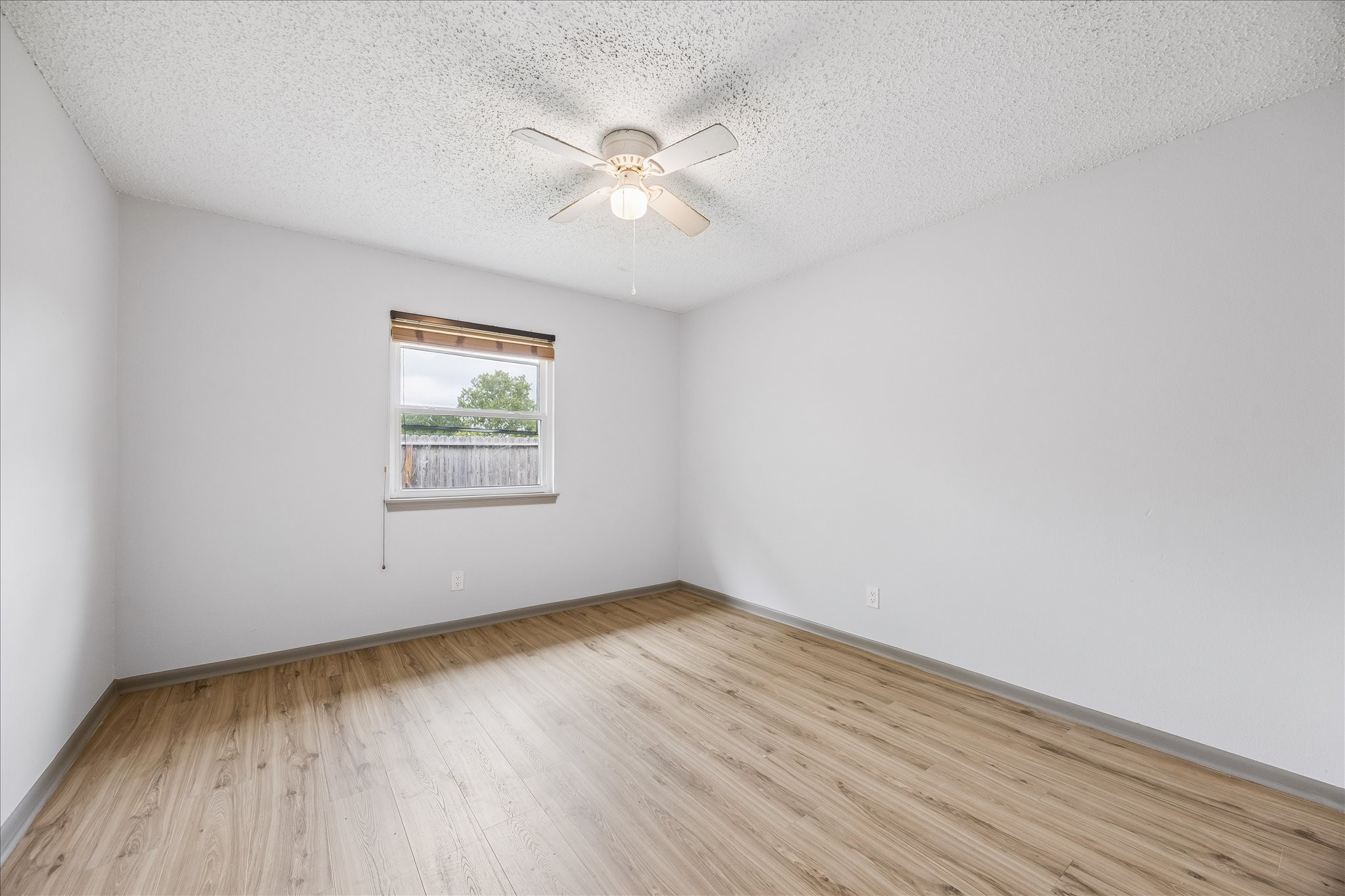 206 Lockett Street Brenham, TX 77833 - Photo 7 of 12 an empty room with wooden floor chandelier fan and windows