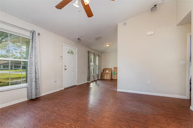 a view of an empty room with wooden floor and a window