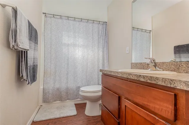 a bathroom with a granite countertop sink a toilet a shower and a mirror