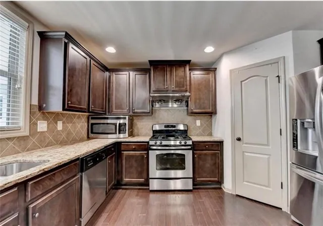 a kitchen with stainless steel appliances a stove a sink and a refrigerator