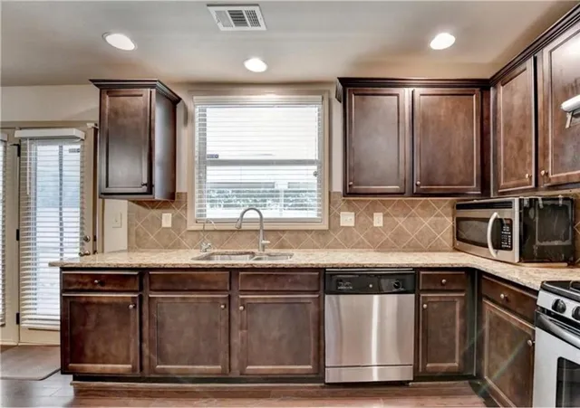 a kitchen with granite countertop a sink stainless steel appliances and cabinets